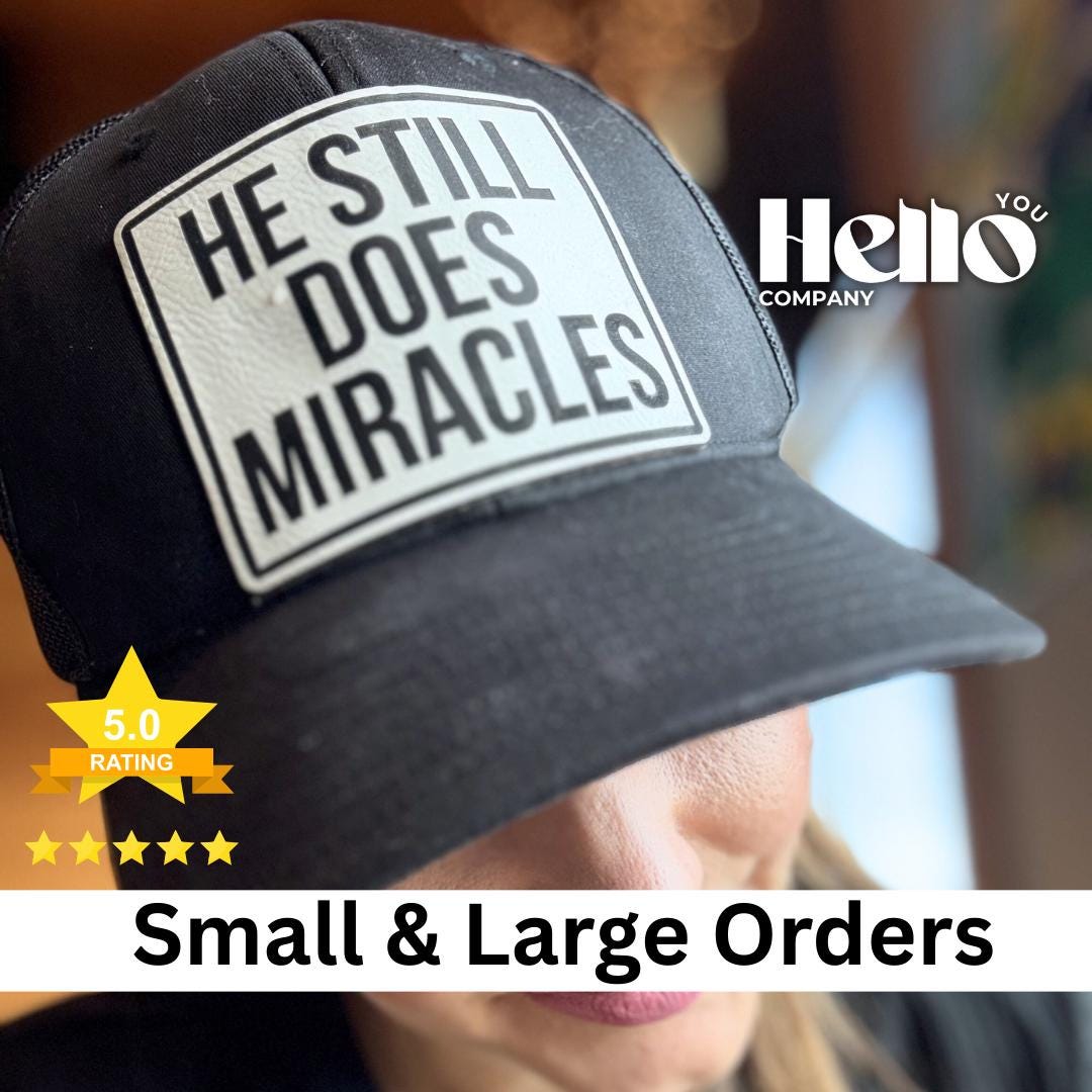 Black trucker hat with a He Still Does Miracles engraved patch