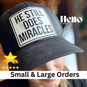 Black trucker hat with a He Still Does Miracles engraved patch