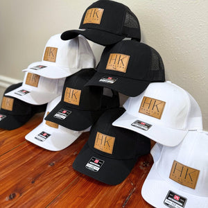 Stack of custom leatherette patch trucker hats with a business logo