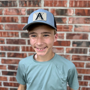 Boy wearing a blue trucker hat with an engraved initial patch