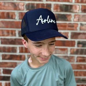 Boy wearing a navy trucker hat with a custom name patch