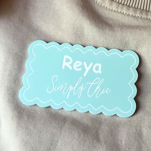 Mint scalloped name badge worn on a sweatshirt