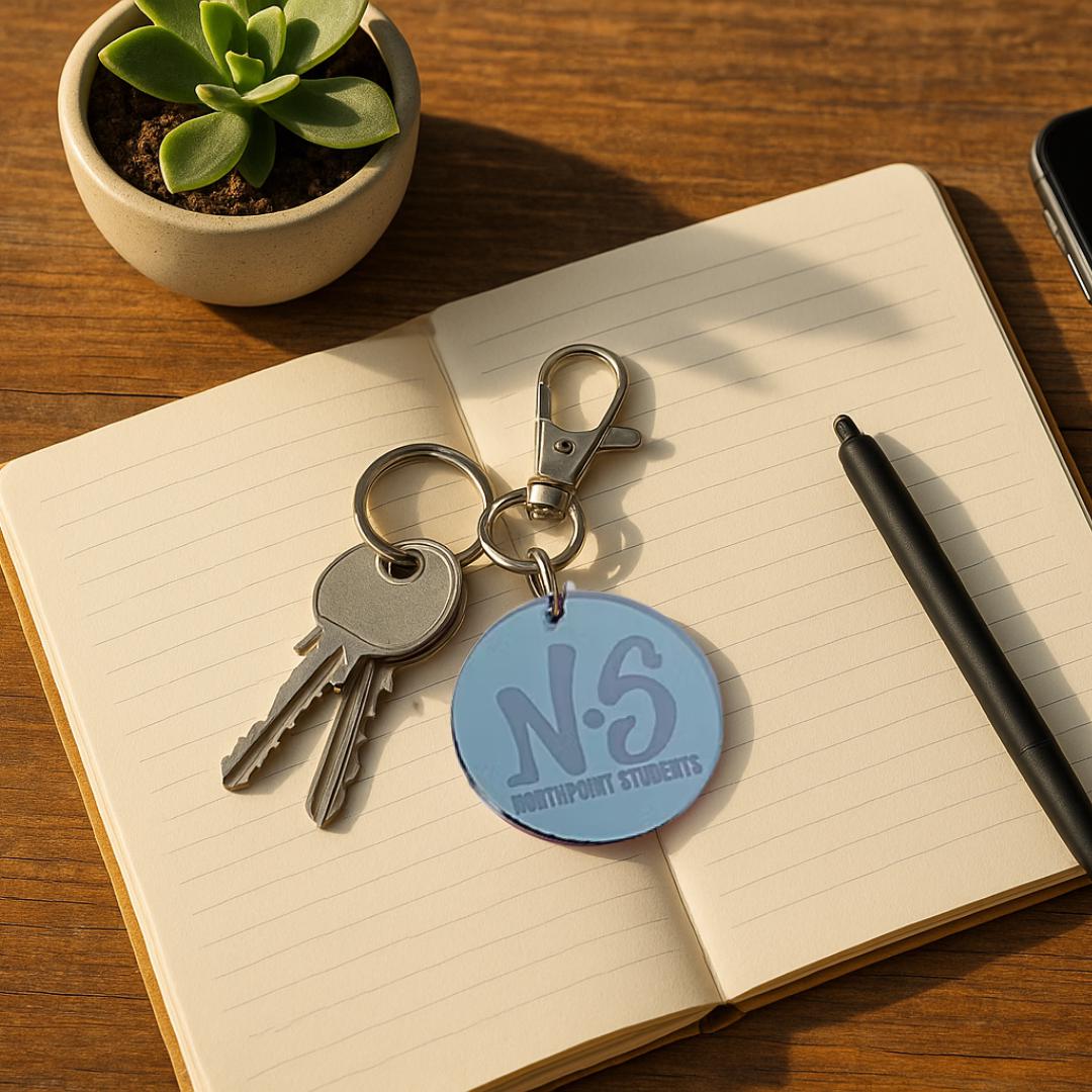 Blue mirror acrylic NS keychain with house keys on a notebook
