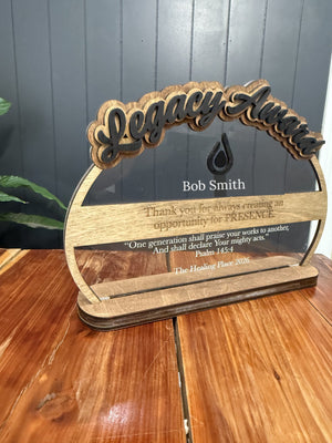 Clear acrylic Legacy Award with a layered wood title, black logo, engraved names and verse, on a wood stand