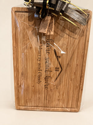 Engraved bamboo cutting board with a juice groove, wrapped in cellophane with a black and gold bow