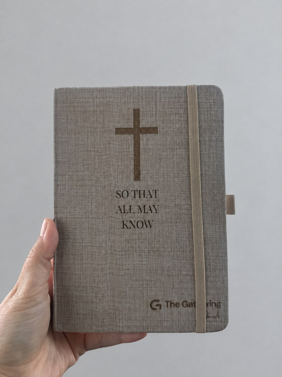 Engraved linen journal held in hand with the elastic band closure