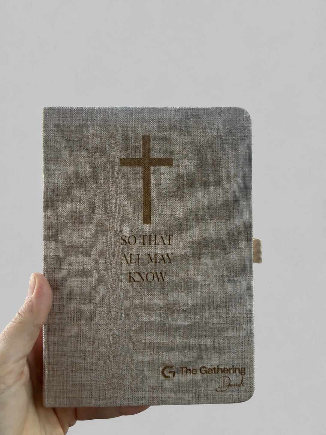 Engraved linen journal held in hand, showing the pen loop on the side