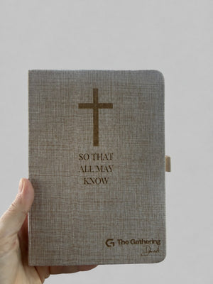 Engraved linen journal held in hand, showing the pen loop on the side