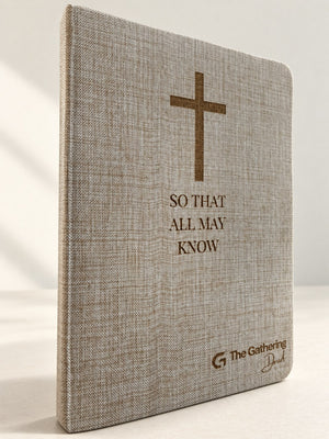 Linen-cover hardcover journal standing on a table, laser engraved with a cross, So That All May Know, and a church logo