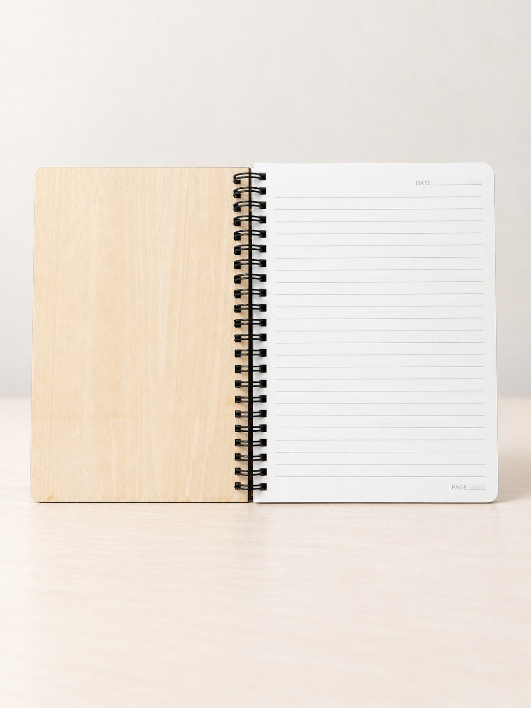 Wood spiral notebook opened to a lined page with a date line at the top and a page line at the bottom
