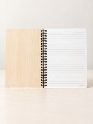 Wood spiral notebook opened to a lined page with a date line at the top and a page line at the bottom