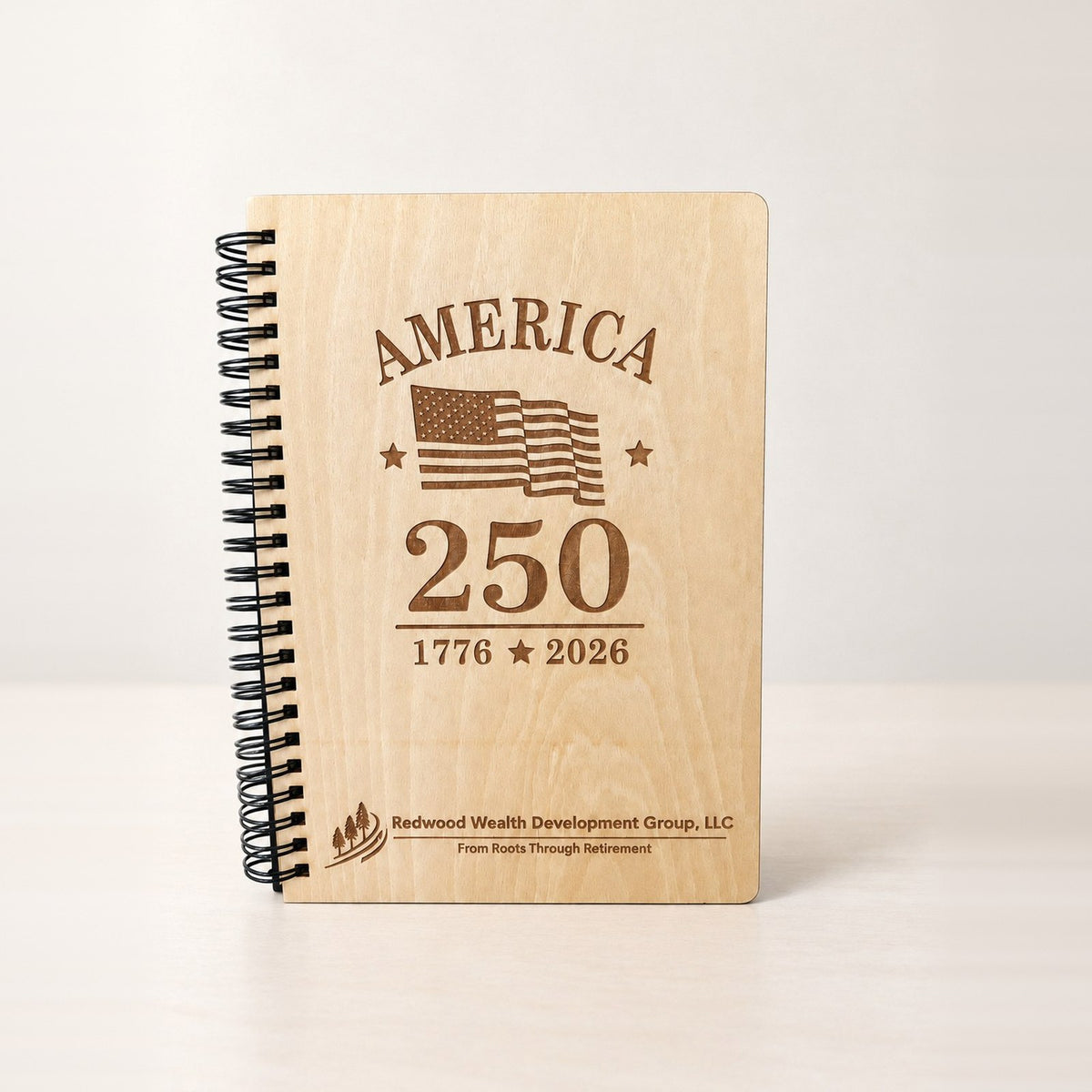 Laser engraved birch wood spiral notebook with a black spiral, America 250 design and a company logo