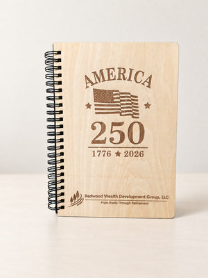 Front of an engraved wood spiral notebook standing upright on a light table