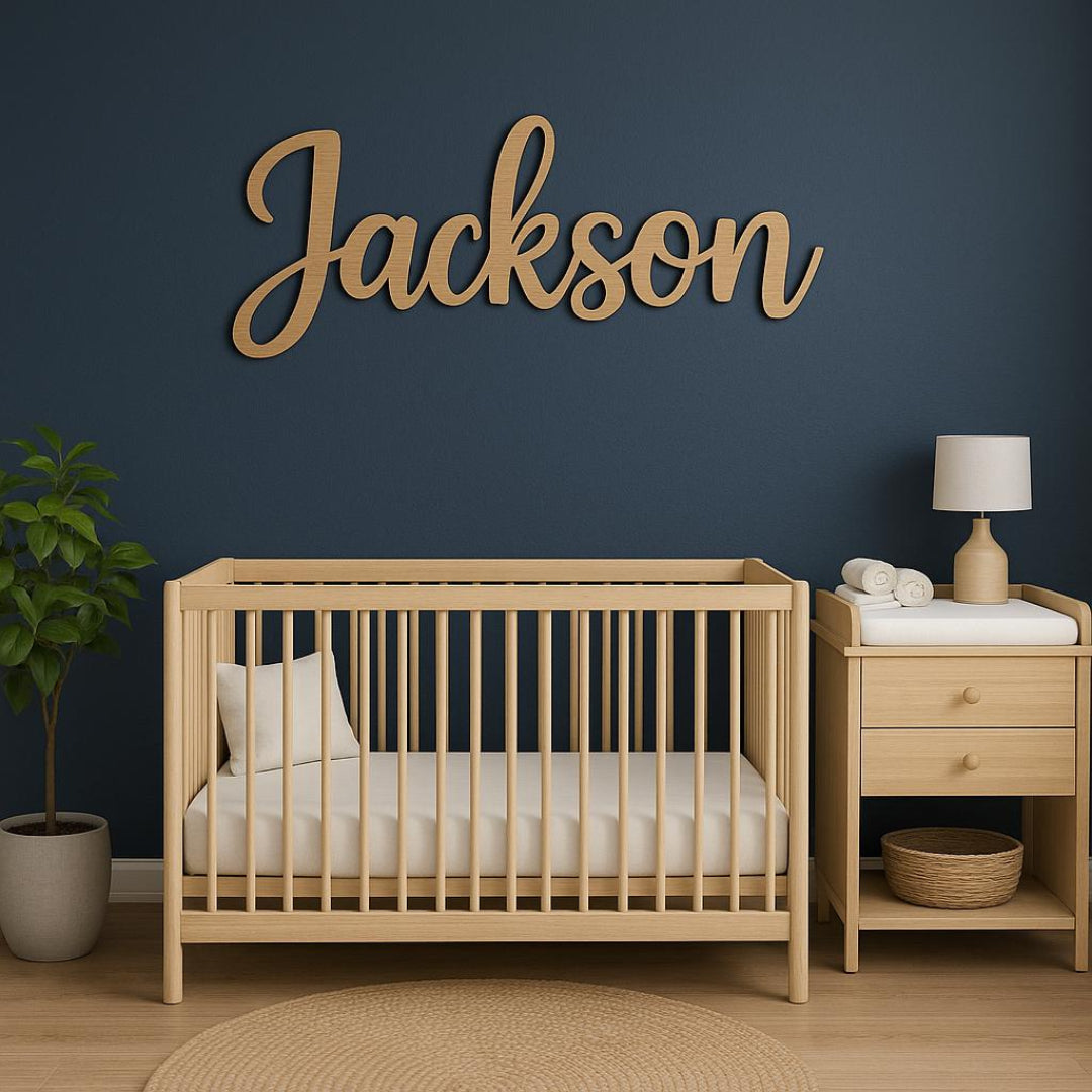 Nursery room with wooden crib, nightstand, and decorative name sign on a dark blue wall.

