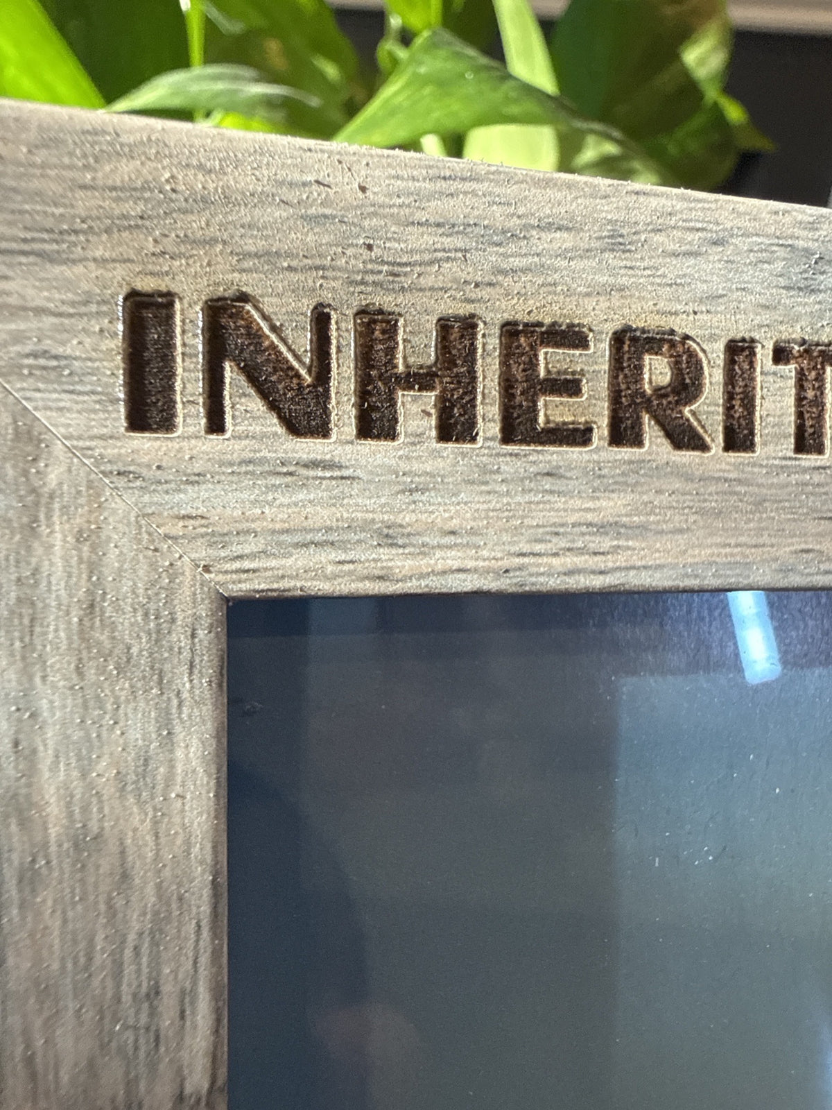 Close-up of laser engraved lettering on the top of a gray wood-grain picture frame