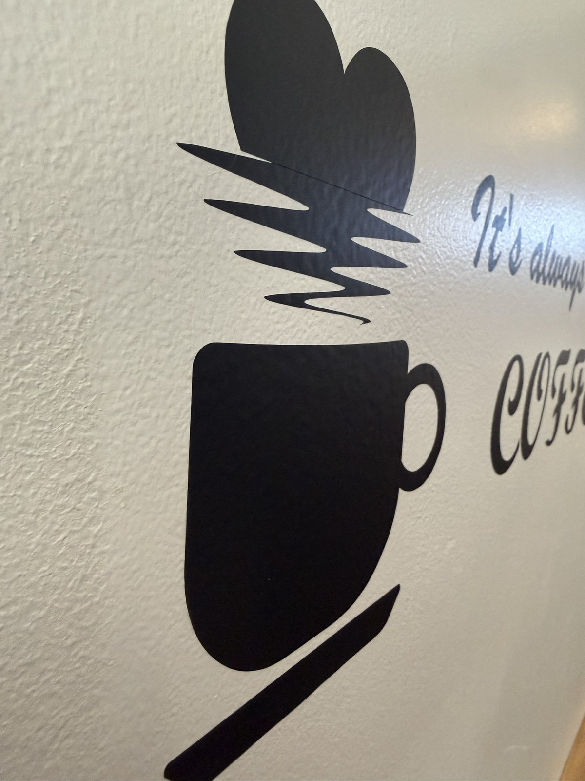 Black vinyl coffee cup and script lettering decal applied to a textured wall